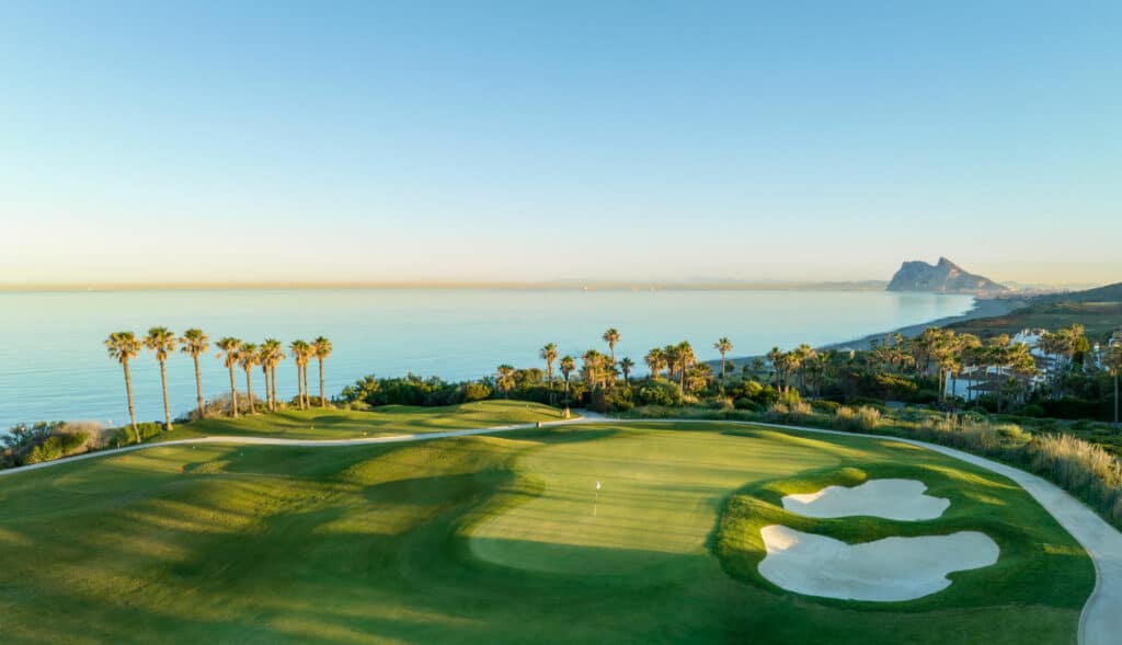 Vista aérea de uno de los hoyos del campo Links de La Hacienda, con vistas al mar y al horizonte, donde el campo de golf se extiende sobre el paisaje costero.